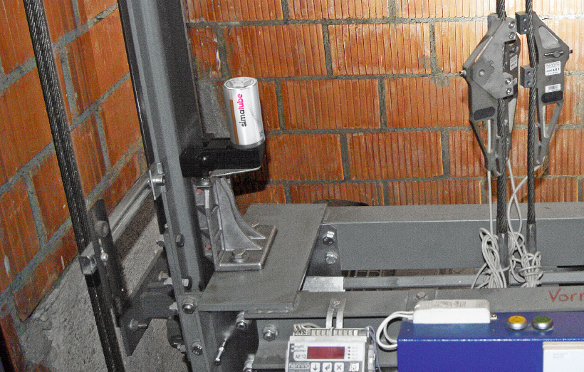 Le graisseur simalube monté sur le sabot de guidage d'un ascenseur lubrifie automatiquement la glissière de guidage de l'ascenseur et, grâce à la brosse d'ascenseur simalube, la glissière est même nettoyée pendant le fonctionnement.